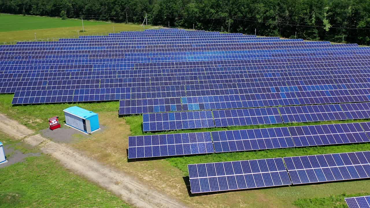 以绿色自然为背景的太阳能电池板农场。在阳光明媚的日子里在野外建造太阳能发电站。成排的太阳能电池板用于发电。替代能源。鸟瞰图。视频素材