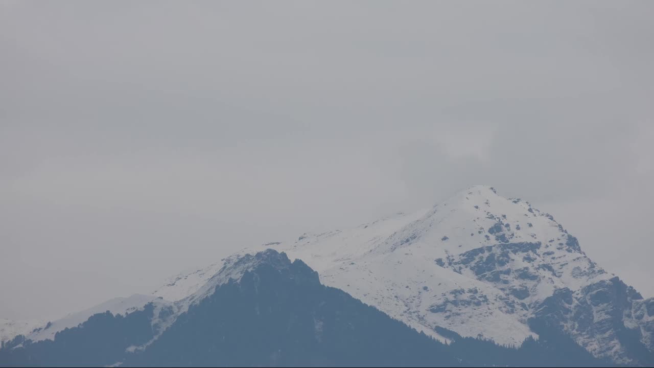 在云雾飘移的同时，喜马拉雅山脉积雪和柔和的阳光照亮了山峰视频素材