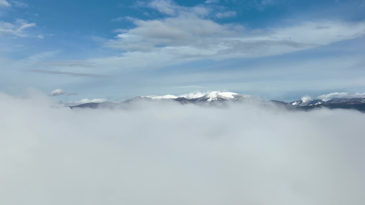 在云层之上飞行，令人惊叹的鸟瞰图，在意大利的一个冬天，积雪覆盖的山脉被云层包围。视频素材