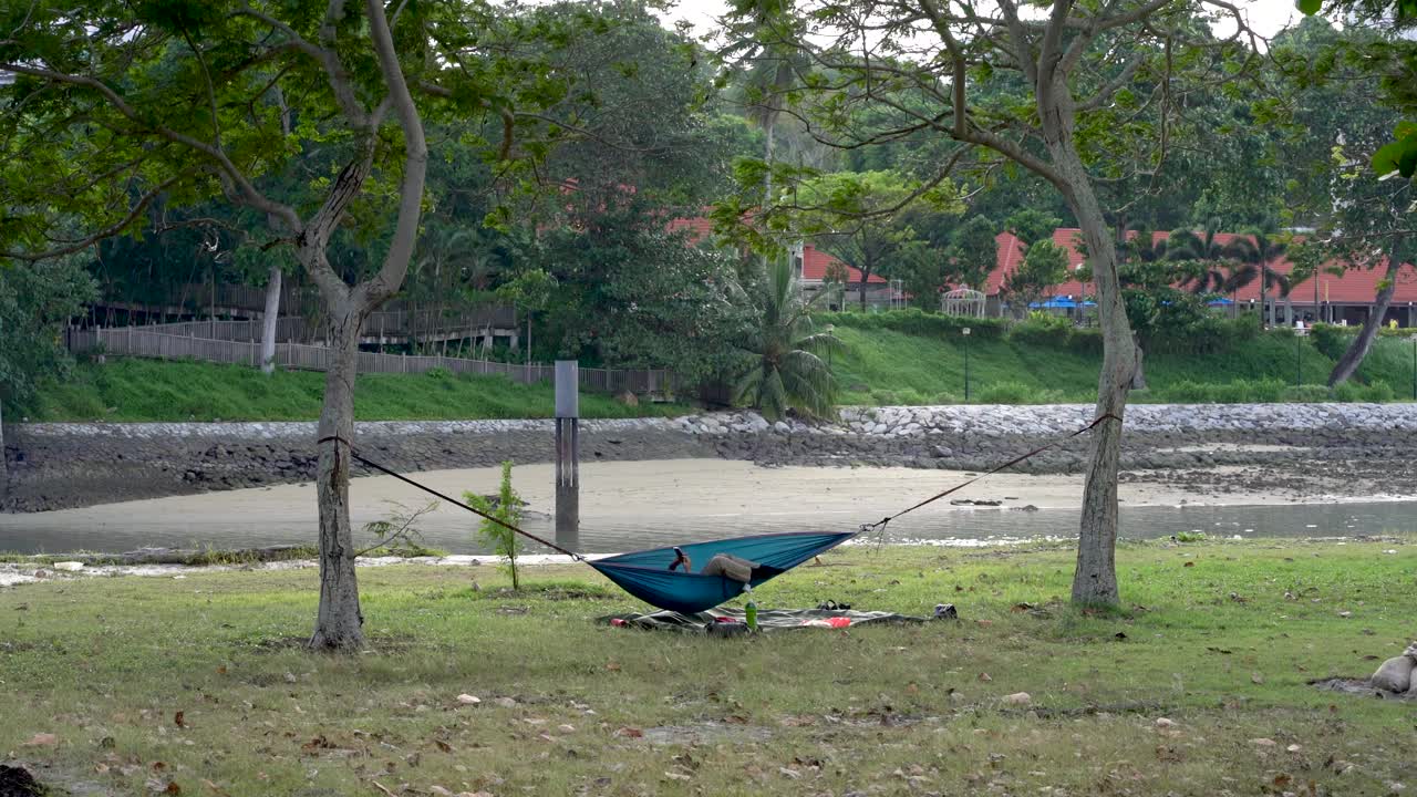 樟宜海滩，一名男子躺在吊床上玩手机视频下载