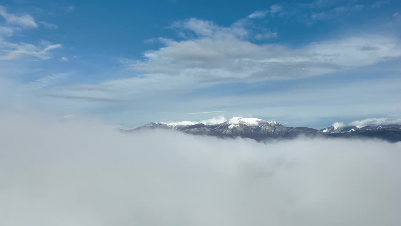 在云层之上飞行，令人惊叹的鸟瞰图，在意大利的一个冬天，积雪覆盖的山脉被云层包围。视频素材