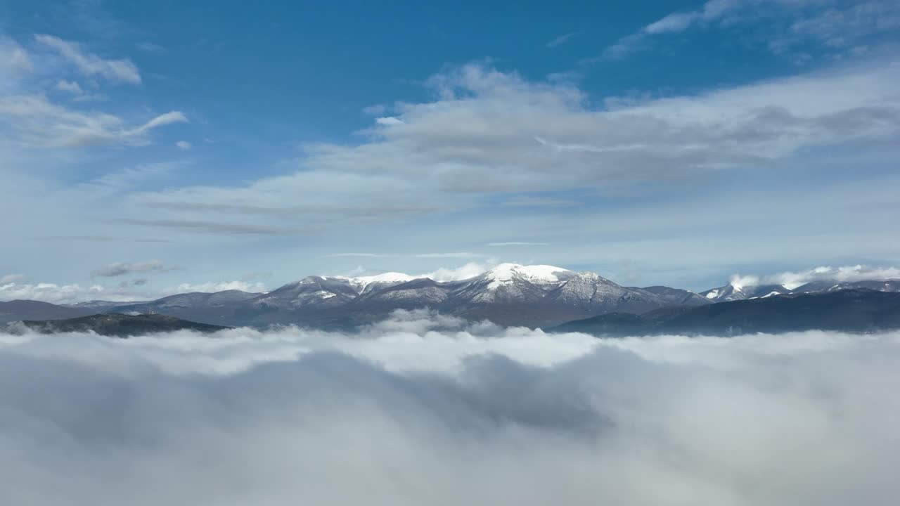 在云层之上飞行，令人惊叹的鸟瞰图，在意大利的一个冬天，积雪覆盖的山脉被云层包围。视频素材