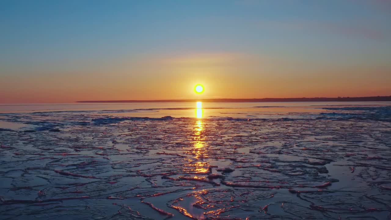 冰封的海面上的夕阳，从海岸线上落下的夕阳，空中的飞行融化的冰，春天温暖的海水，冬天的日落，天空和海洋的色彩。无人机视频视频素材