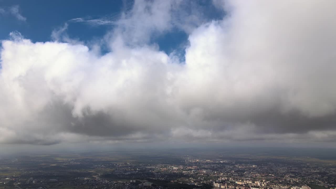 高空鸟瞰图，远处的城市被暴雨前形成的蓬松的积云所覆盖视频素材