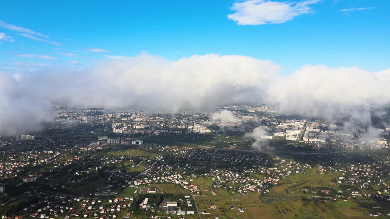 高空鸟瞰图，远处的城市被暴雨前形成的蓬松的积云所覆盖。视频素材