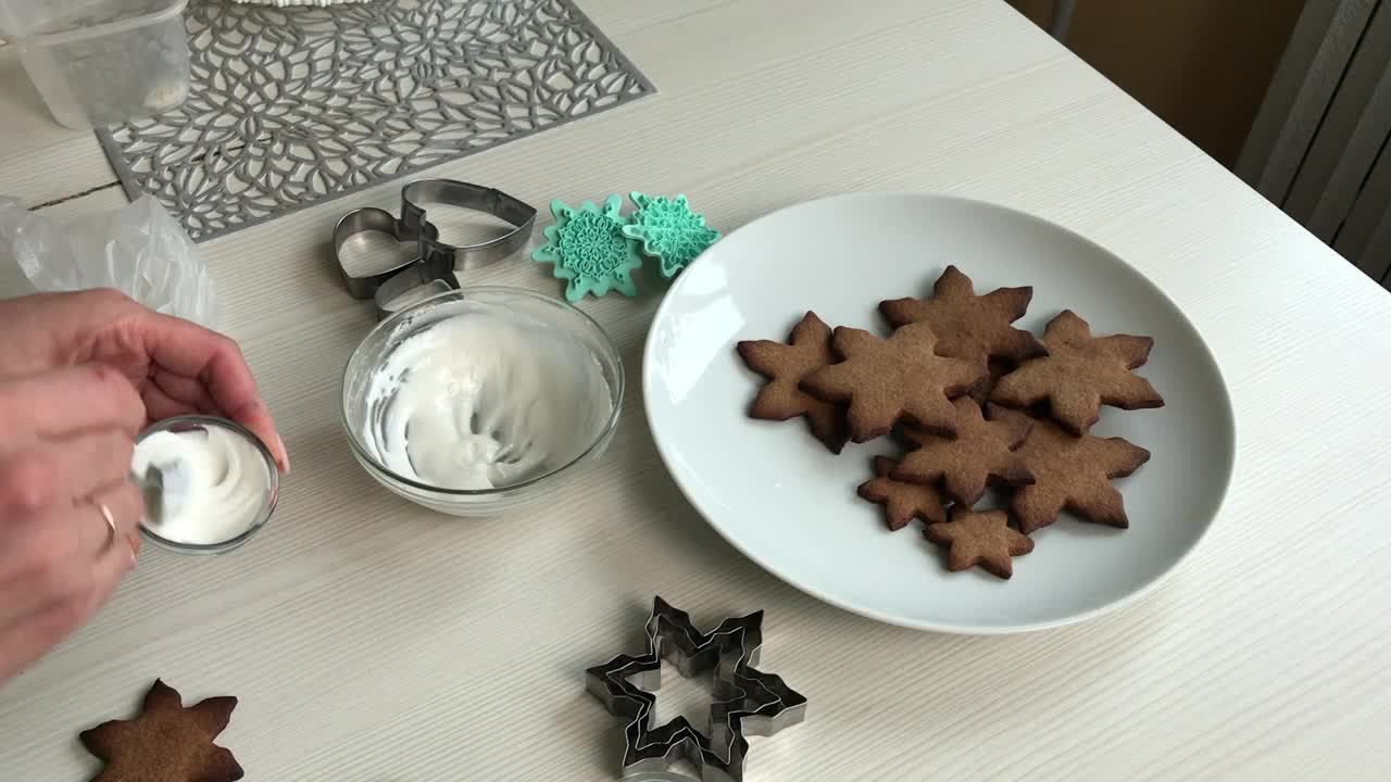 这名妇女使用食用色素。准备装饰姜饼的糖霜。旁边是雪花形状的姜饼。总体规划视频素材