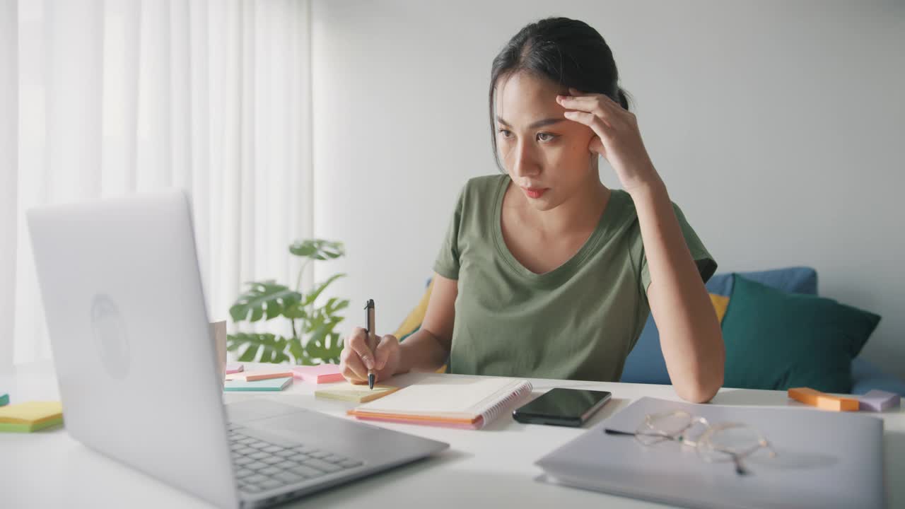 疲倦的年轻亚洲商业妇女在休闲工作笔记本电脑在客厅在家里。视频素材