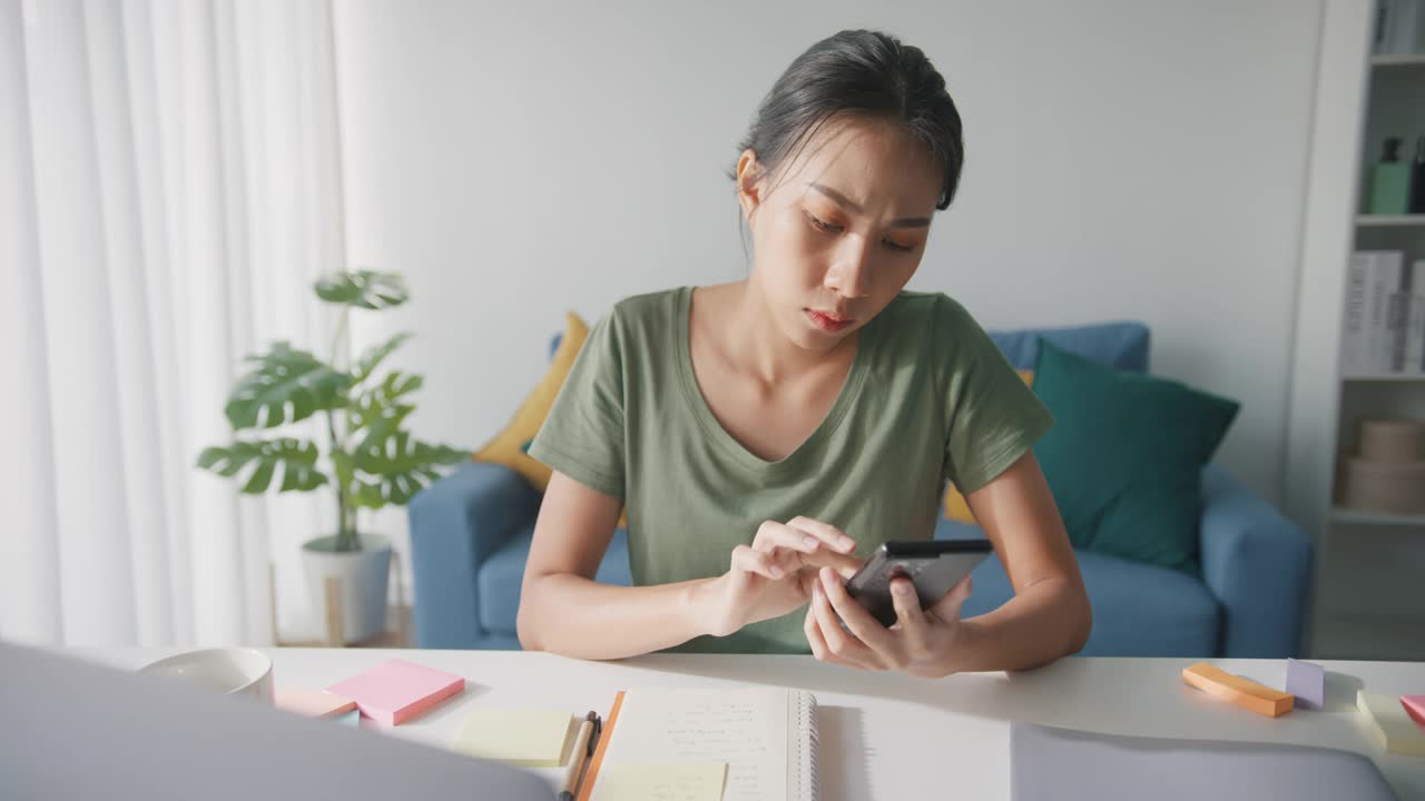 疲倦的年轻亚洲商业妇女在休闲使用电话在客厅在家里。视频素材