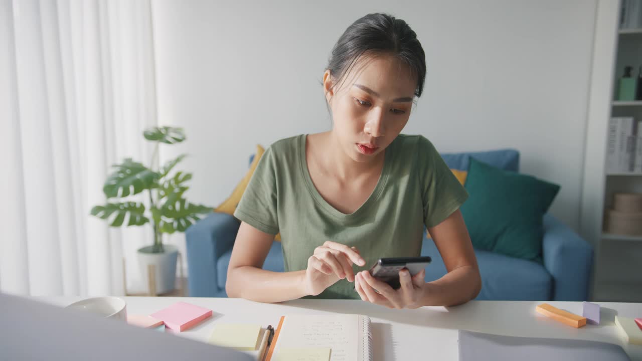 疲倦的年轻亚洲商业妇女在休闲使用电话在客厅在家里。视频素材