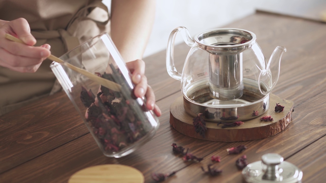 红茶的冲泡工艺。第一步。管家用勺子从玻璃罐里洒出干木槿茶视频素材