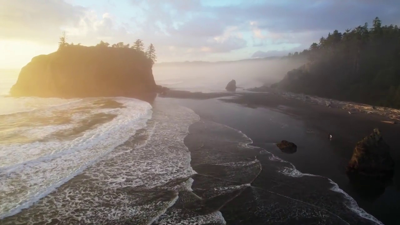 美国俄勒冈州，在夕阳下飞过红宝石海滩。美丽的黑色海滩在雾，悬崖和太平洋的波浪。空中无人机拍摄的视频素材