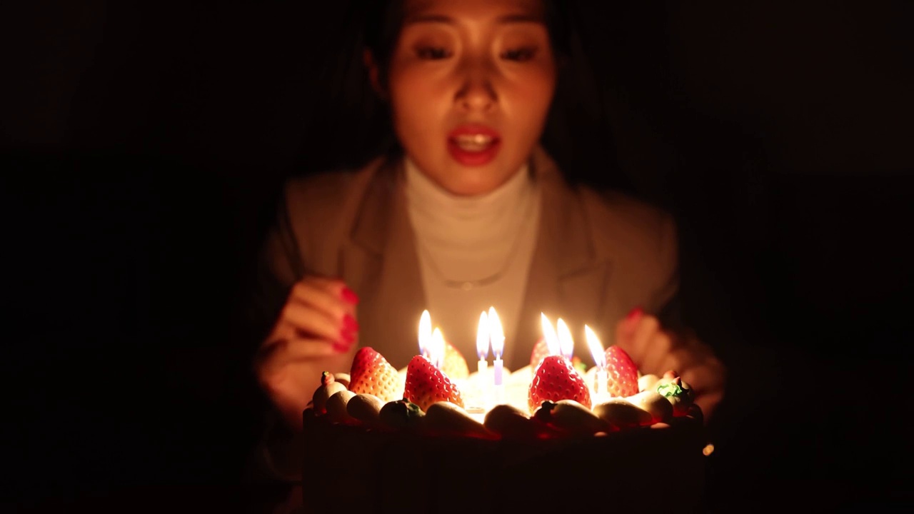 吹生日蛋糕上的蜡烛的女人视频素材