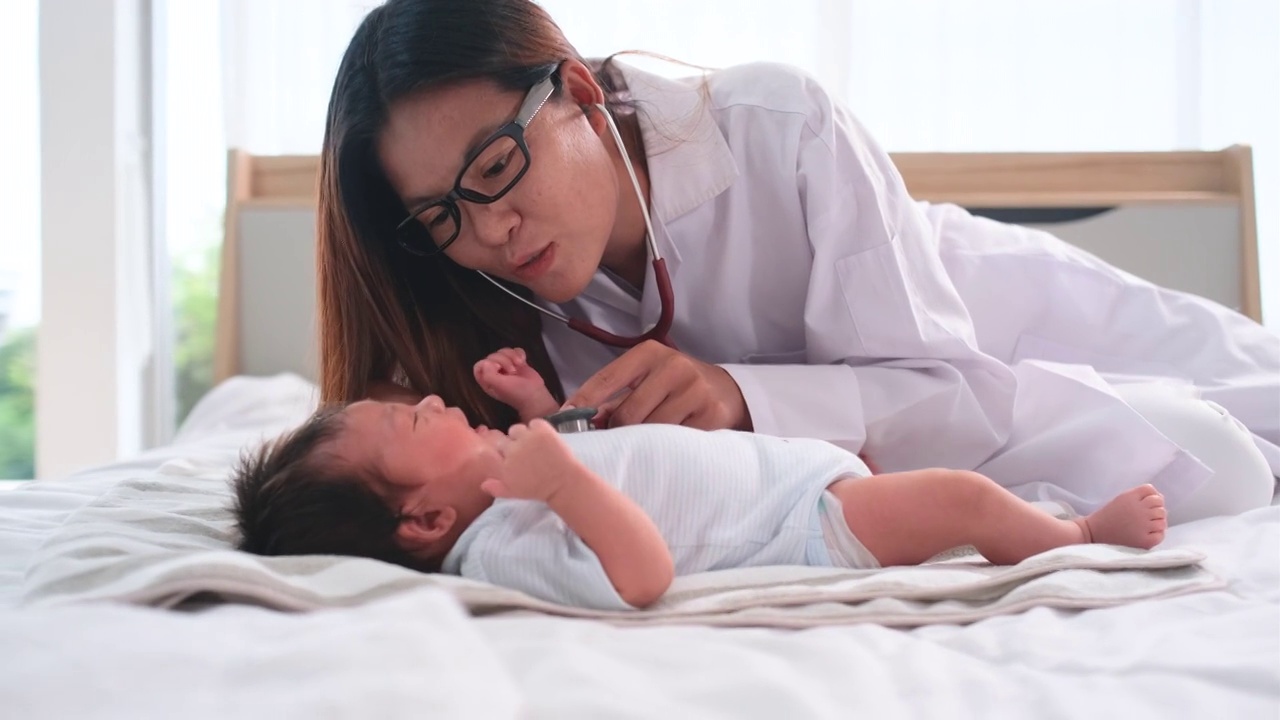 亚洲医生使用听诊器检查新生儿躺在床上的症状进行诊断和治疗视频素材画面1