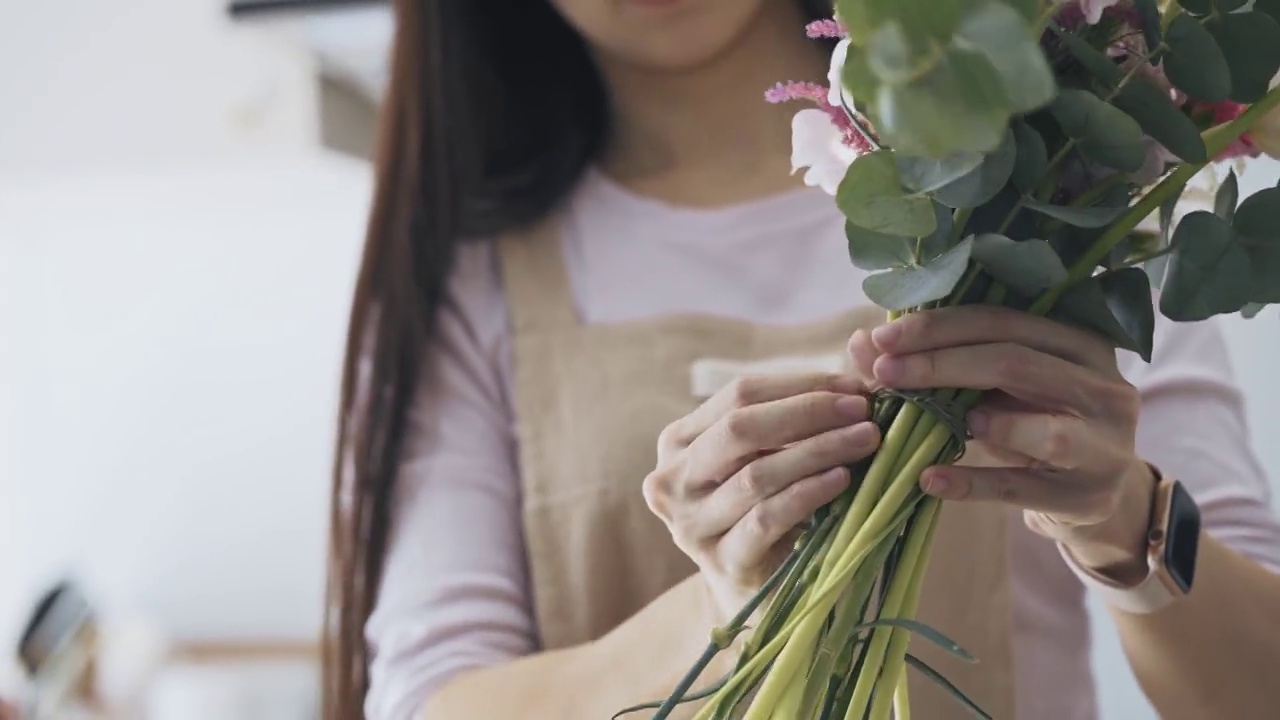 关闭亚洲女性花店，店主小生意花店，绑花花束。日常事务经营小企业的日常事务视频素材画面1