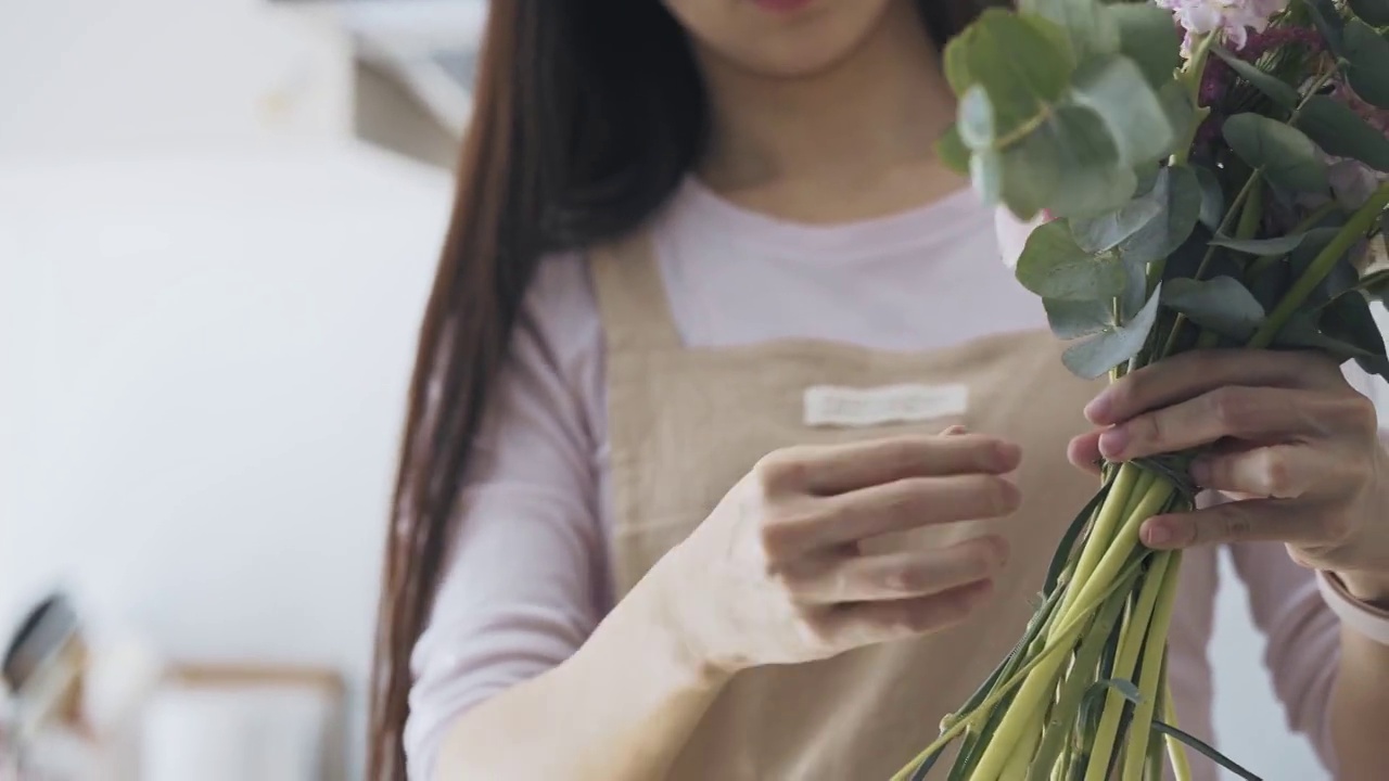 关闭亚洲女性花店，店主小生意花店，绑花花束。日常事务经营小企业的日常事务视频素材画面4