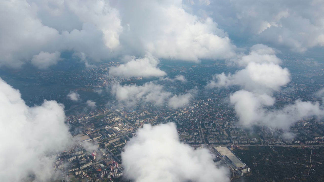 从高空的飞机窗口鸟瞰，远处的城市被暴雨前形成的蓬松的积云所覆盖视频素材