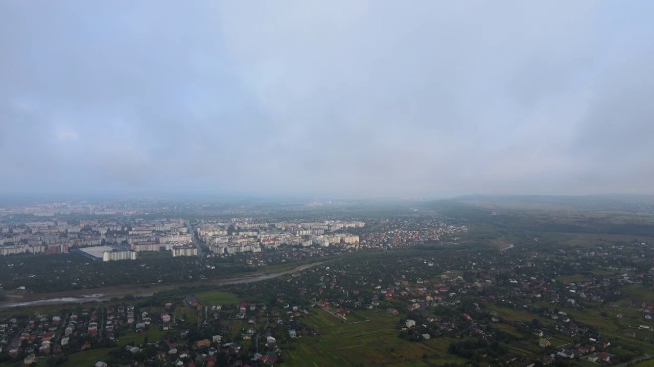 高空鸟瞰图，远处的城市被暴雨前形成的蓬松的积云所覆盖视频素材