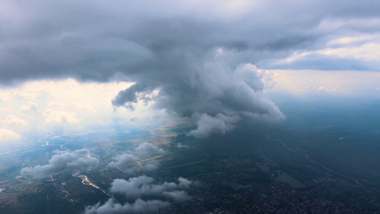 从高空的飞机窗口鸟瞰，远处的城市被暴雨前形成的蓬松的积云所覆盖视频素材