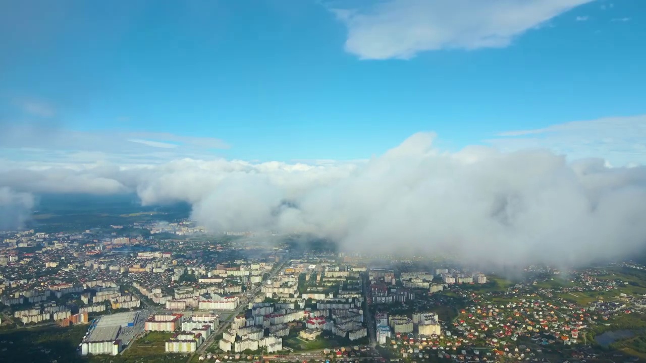 高空鸟瞰图，远处的城市被暴雨前形成的蓬松的积云所覆盖视频素材