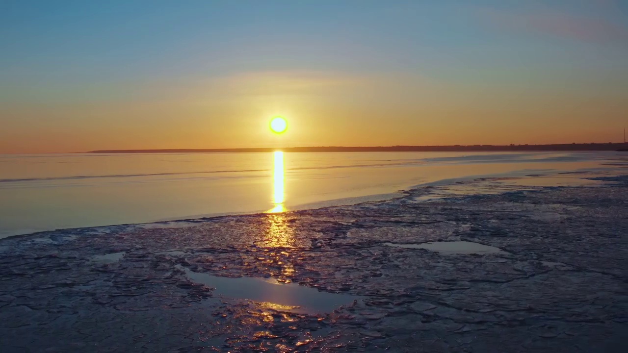 冰封的海面上的夕阳，从海岸线上落下的夕阳，空中的飞行融化的冰，春天温暖的海水，冬天的日落，天空和海洋的色彩。无人机视频视频素材