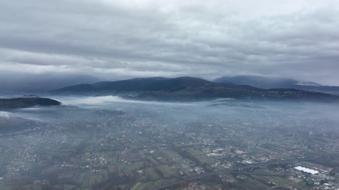 从空中俯瞰，在一个多云的日子里，从空中俯瞰一个美丽的山谷和远处的山脉。视频素材