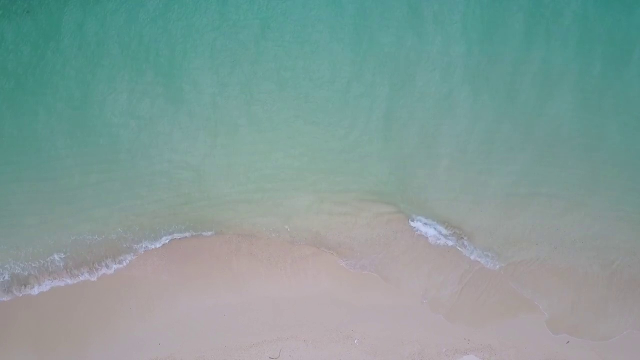 蓝绿色的海浪到达海岸线的鸟瞰图视频素材