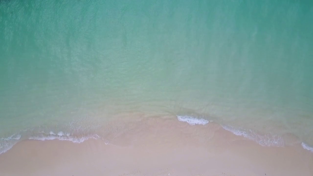 蓝绿色的海浪到达海岸线的鸟瞰图视频素材