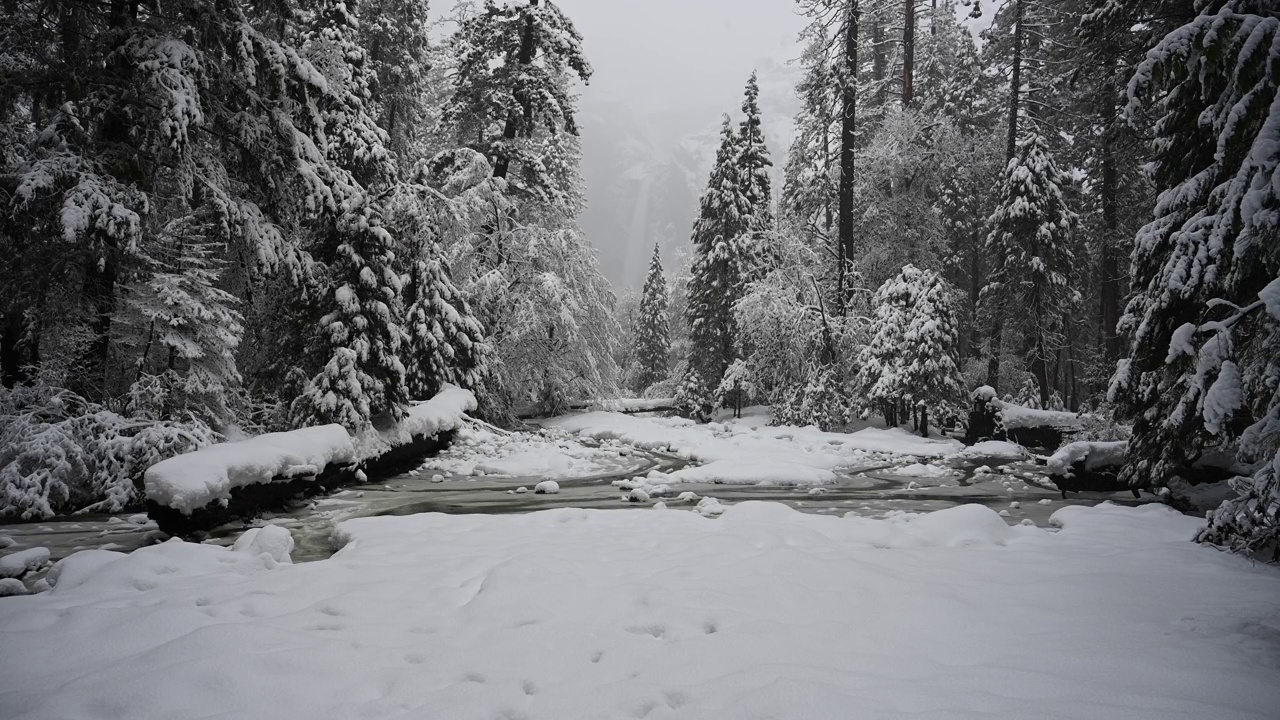 雪落在冰冻的小溪和优胜美地瀑布上视频素材