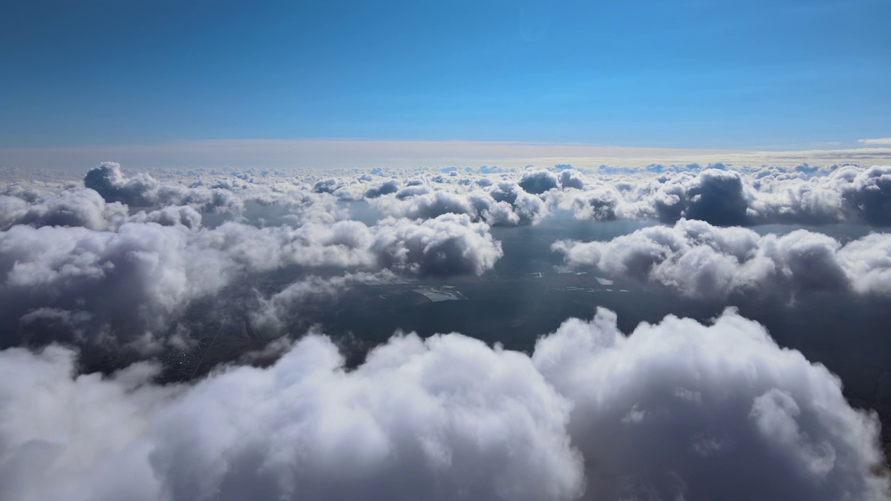 从飞机窗口高空俯瞰，在暴雨前形成的蓬松的积云覆盖着大地视频素材