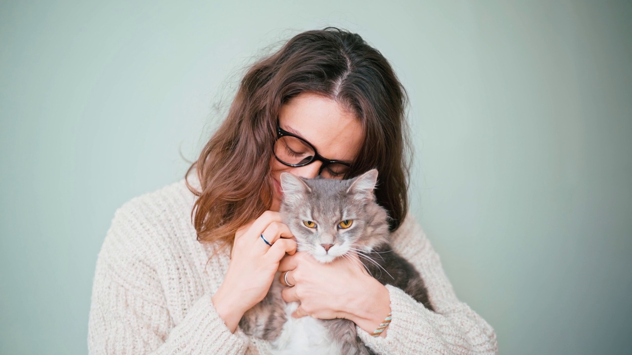 一个迷人的年轻女子抚摸着她的猫。视频素材