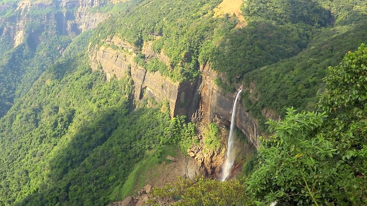 孤零零的瀑布从山顶坠落，从山顶角度依偎在绿色的森林中视频素材