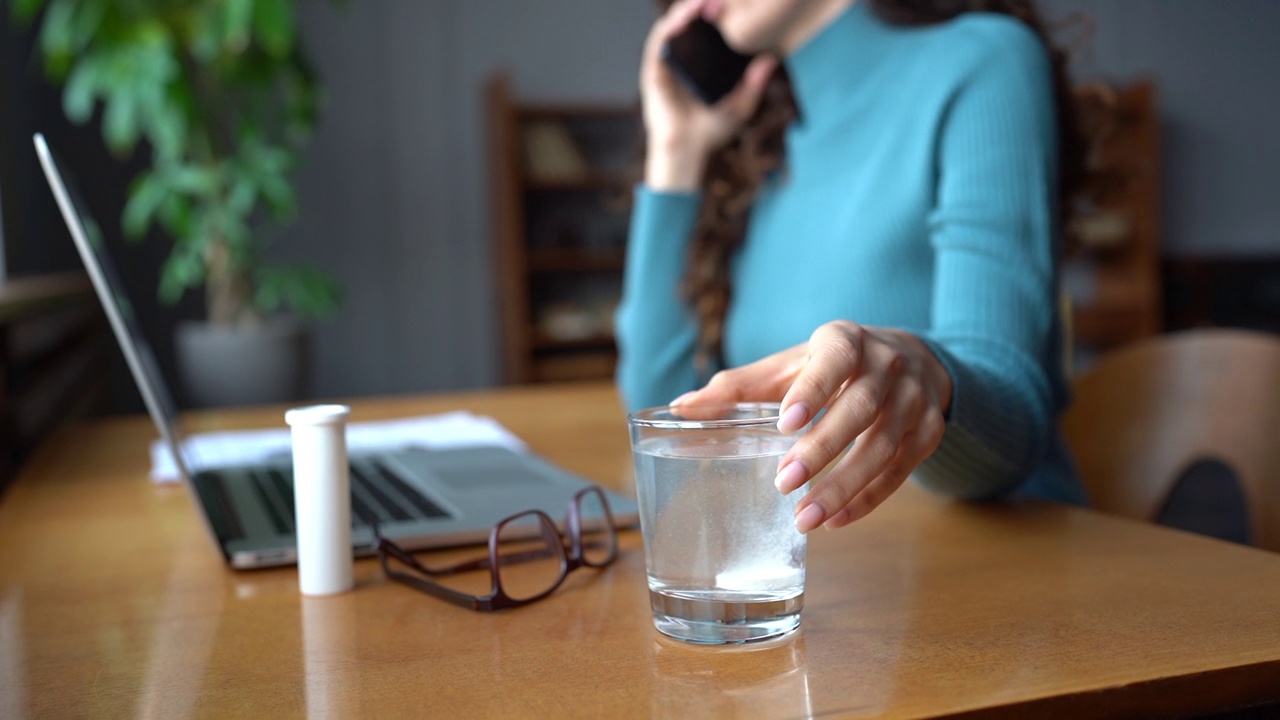 生病的女孩把抗生素或阿斯匹林的止痛药放在玻璃杯里，以缓解宿醉、发烧或流感视频素材