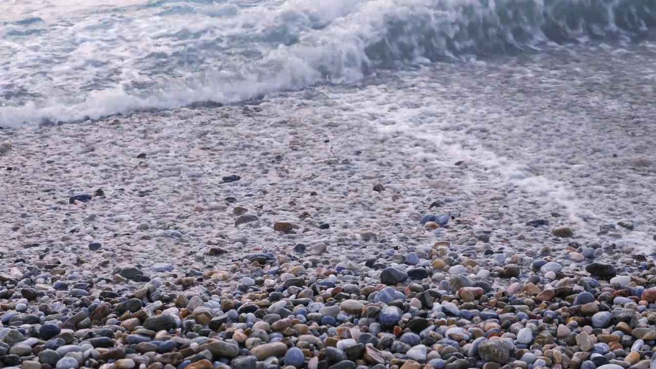 海浪在海边，沙滩上有石头。海浪拍打着卵石滩。鹅卵石和海浪视频素材