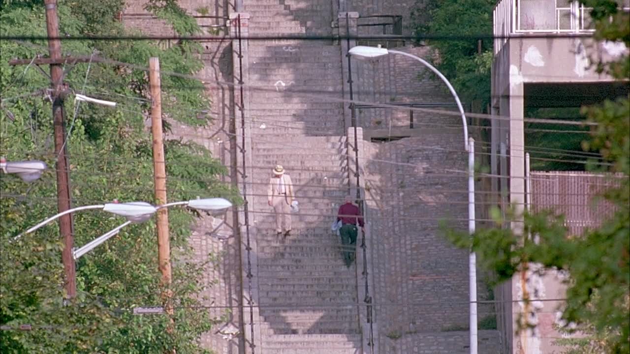 将室外楼梯往后拉，有男子正在下楼。被过往车辆遮挡的视野。视频素材画面1