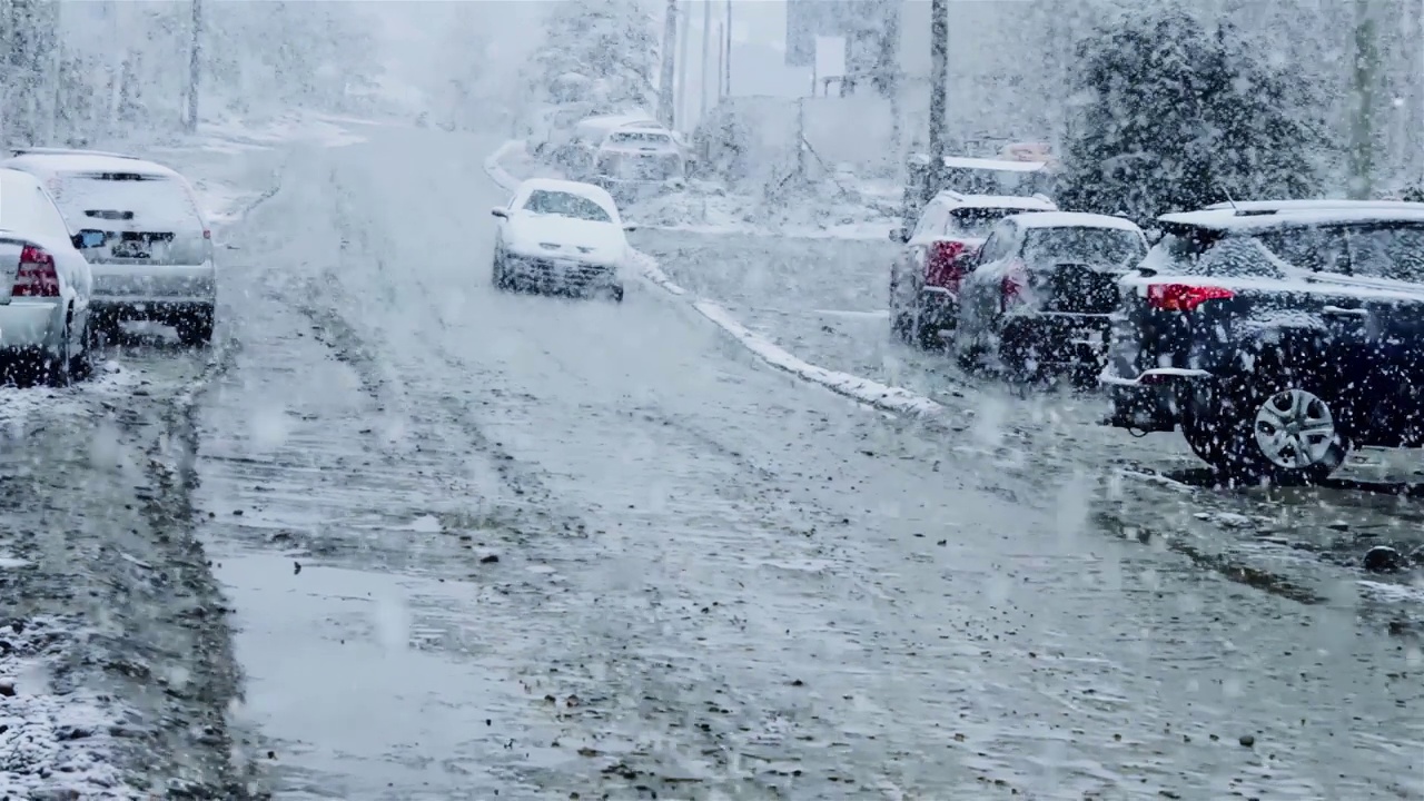 在阿根廷火地岛乌斯怀亚的街道上，汽车在大雪中缓慢行驶。放大，4K分辨率。视频素材