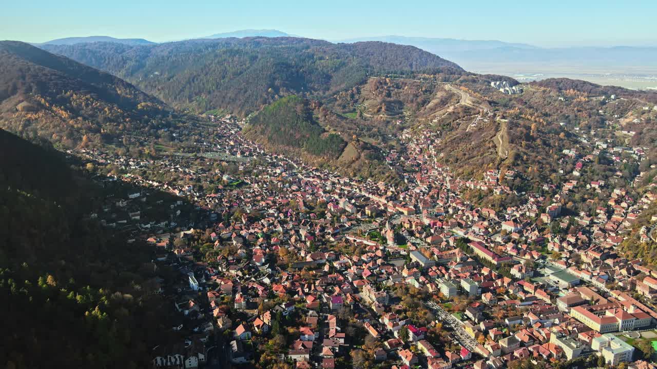 无人机拍摄的罗马尼亚布拉索夫。住宅建筑，黄色的树木，喀尔巴阡山脉视频素材