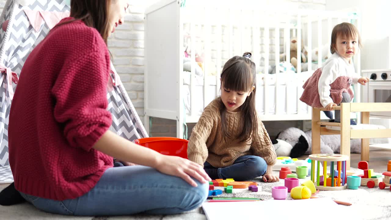 母亲和她的两个女儿在孩子们的房间里玩耍视频素材