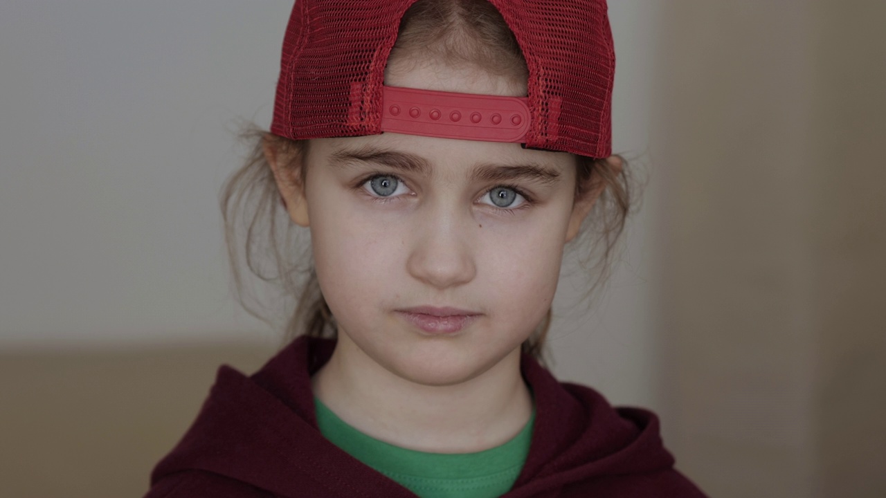 年轻严肃的女孩，戴着红色棒球帽，一头金发，看着室内的摄像机。肖像可爱严肃的孩子严肃的沉思
担心白人少年。悲伤自信的小女孩。人类的脸。视频素材