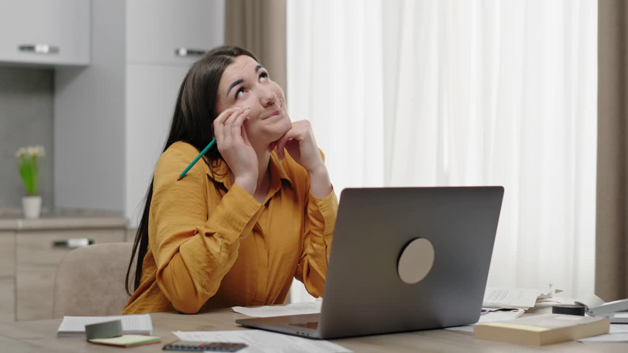 一个年轻的女人坐在桌子旁看着笔记本电脑，害怕地看着屏幕，害怕地用手捂着脸，关上了笔记本电脑视频素材