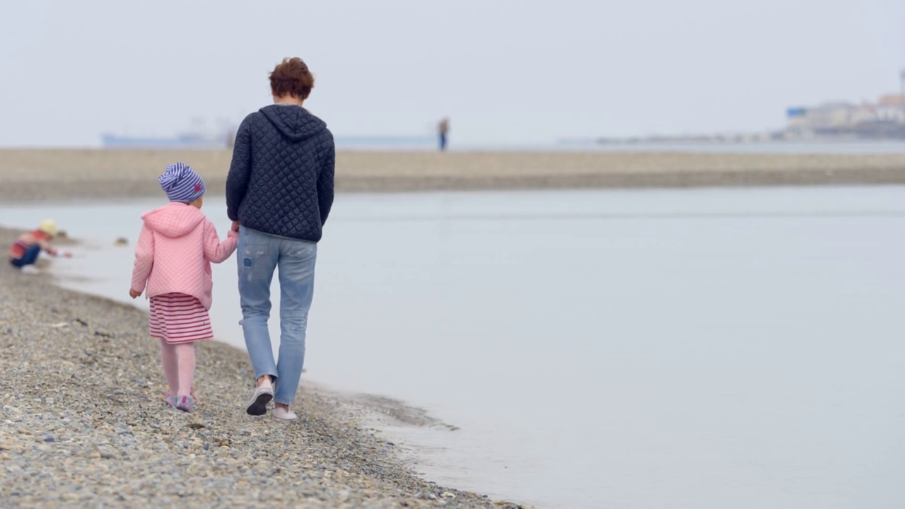 沙滩上的母女:年轻的妈妈带着女儿散步视频素材