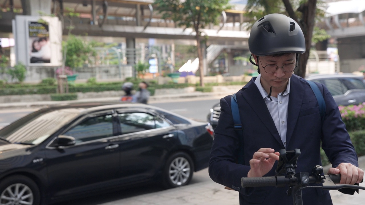 亚洲男子在大城市使用手机和骑电动滑板车视频素材