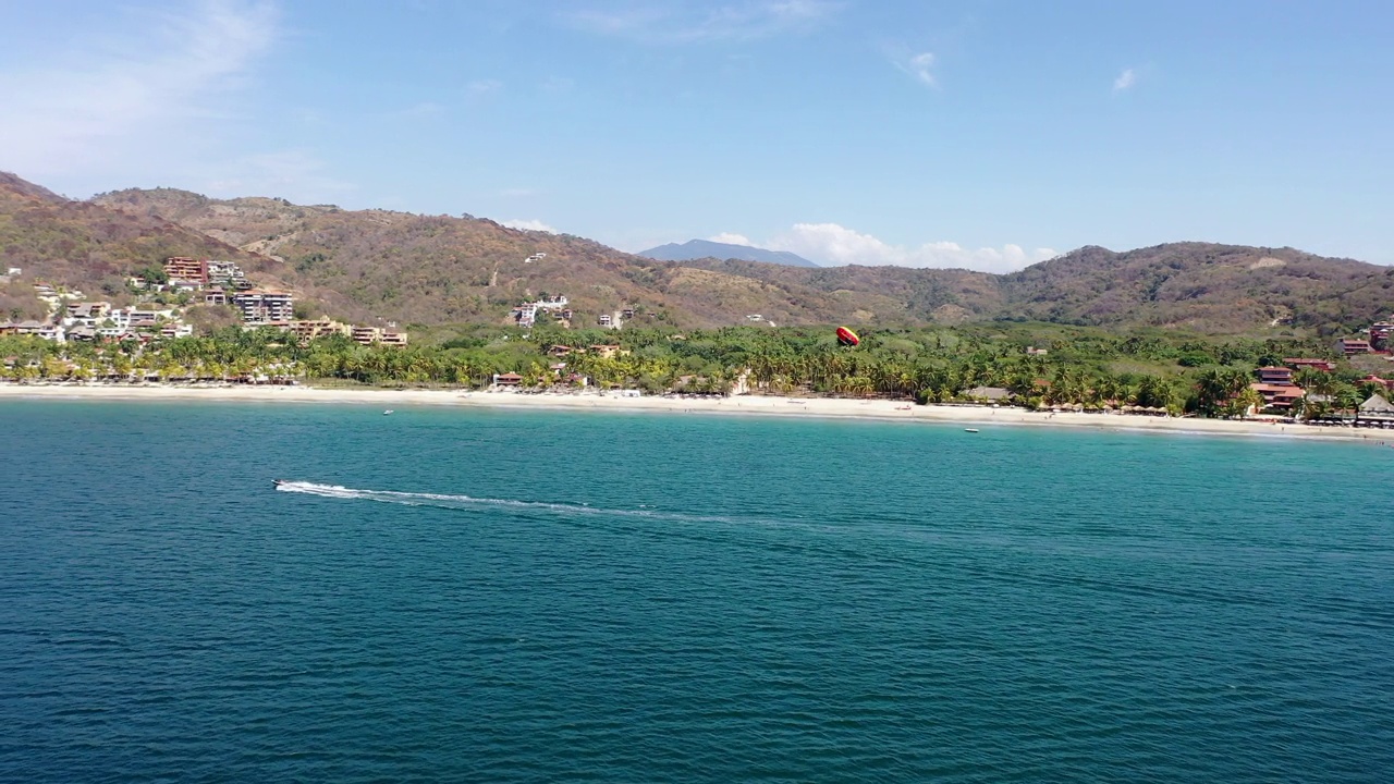 鸟瞰图，在墨西哥的Zihuatanejo，拉着帆伞的人在水面上滑行视频素材