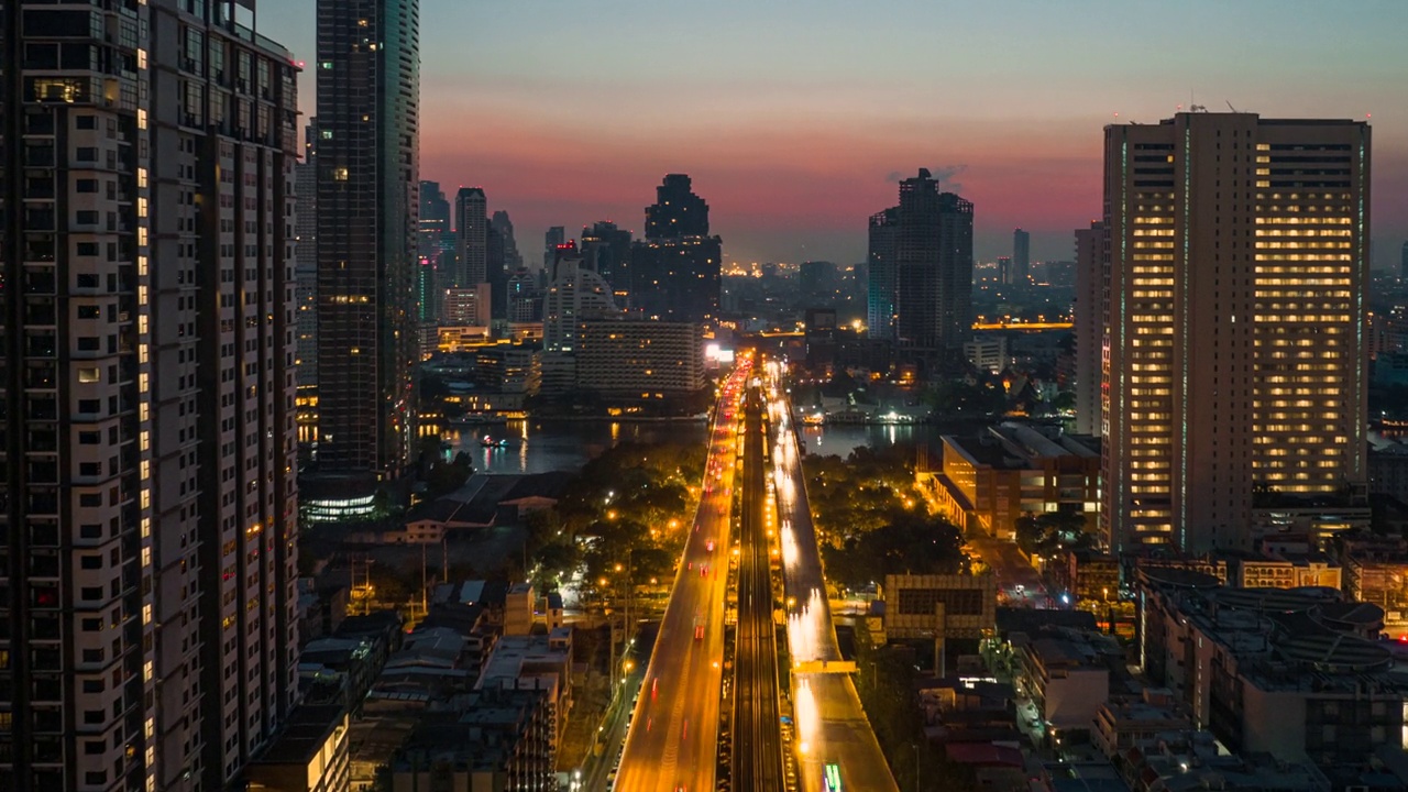 无人机超时间延时拍摄的日出场景，交通车灯在高速公路和地铁空中列车跨越湄南河在曼谷视频素材