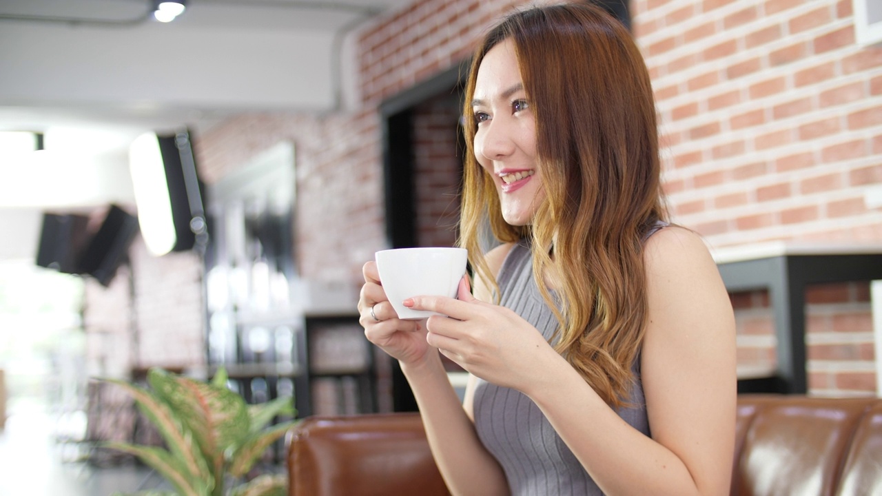 女人喝咖啡，享受Tatse，年轻的女人放松在咖啡馆视频素材