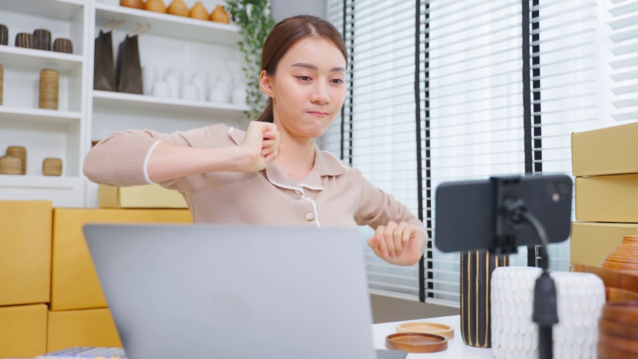 亚洲美女在家在线直播卖花瓶产品。年轻漂亮的女孩用笔记本电脑向顾客展示商品并呈现细节。远程购买和购买购物概念视频素材