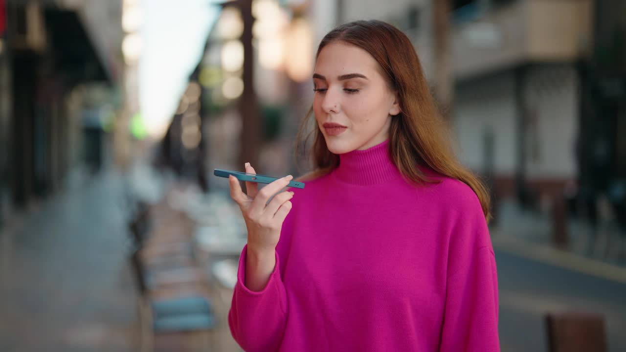 年轻的金发女子微笑着自信地在街上用智能手机聊天视频素材