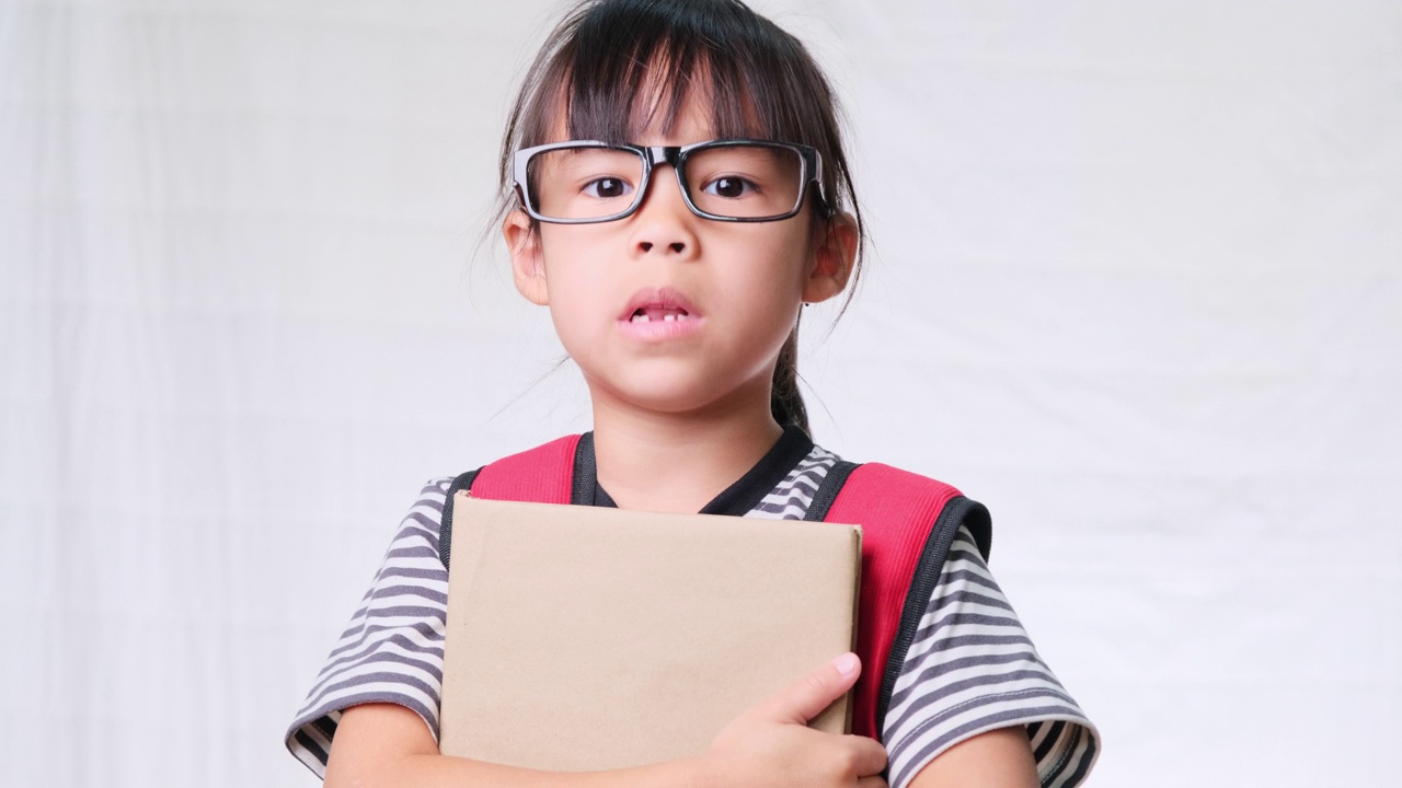 沮丧的女学生穿着休闲的衣服，背包里拿着白色背景的书在工作室里，不想去学校回到学校的概念视频素材