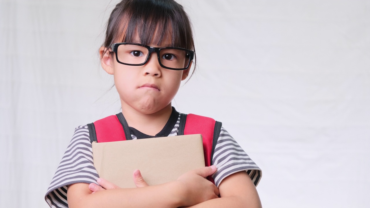 沮丧的女学生穿着休闲的衣服，背包里拿着白色背景的书在工作室里，不想去学校回到学校的概念视频素材