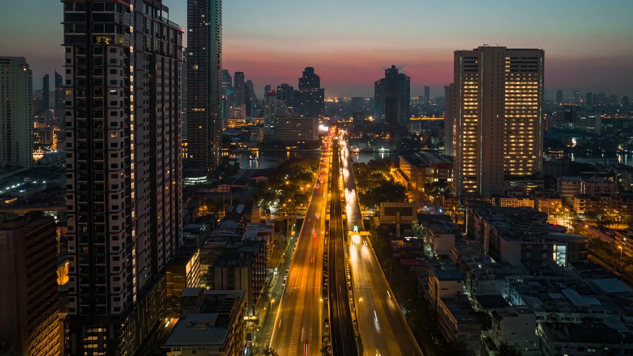 无人机超时间延时拍摄的日出场景，交通车灯在高速公路和地铁空中列车跨越湄南河在曼谷视频素材