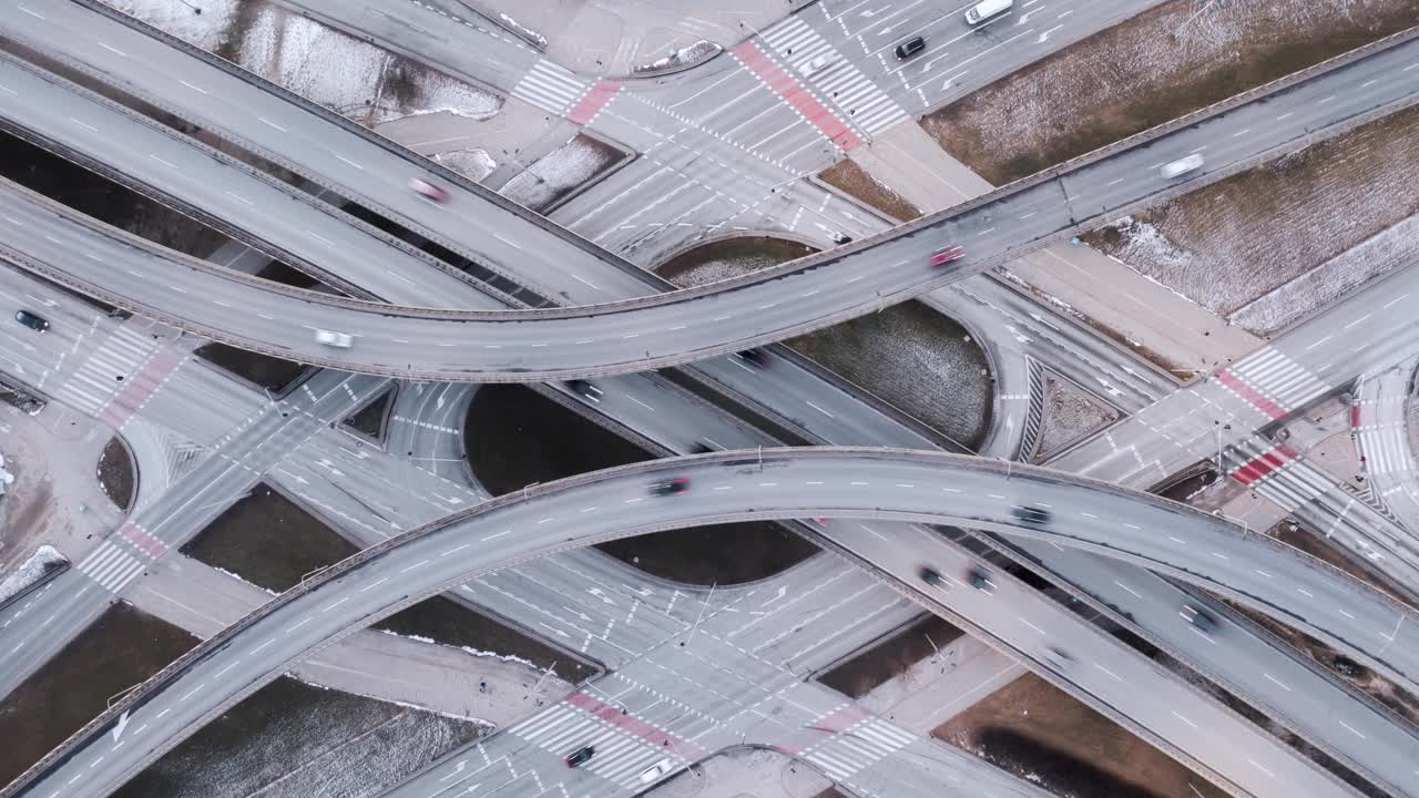 空中时间推移交通堵塞的立交道路，无人机拍摄在现代城市的道路交叉口傍晚自上而下缩小视野。穿梭的汽车在繁忙的环形交叉口高速公路上快速行驶视频素材